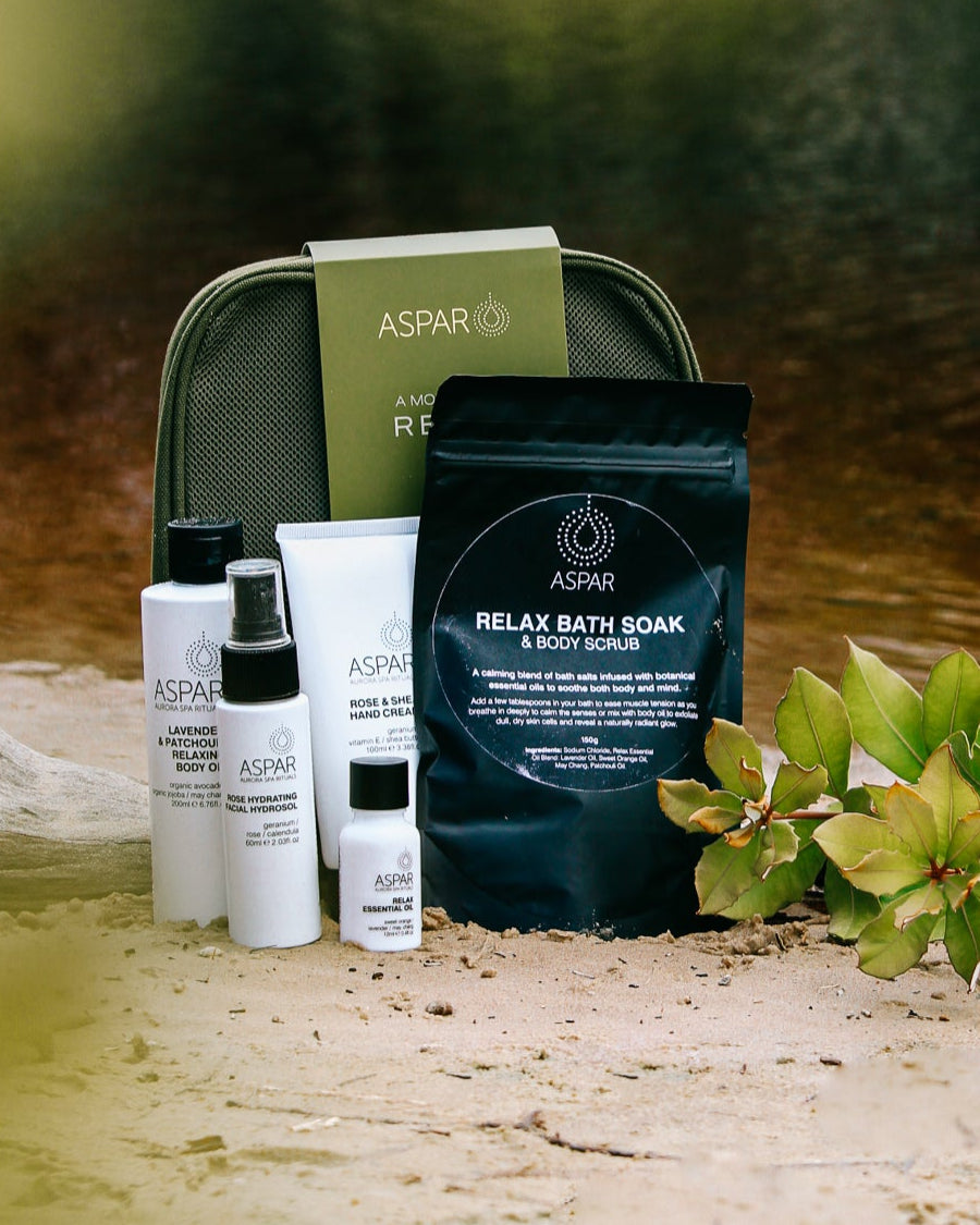 Cosmetic products and a bag on a sandy beach with water in the background