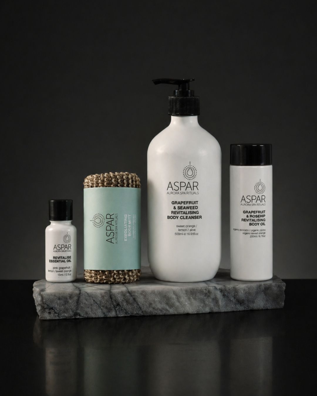 Collection of Aspar skincare products on a dark background