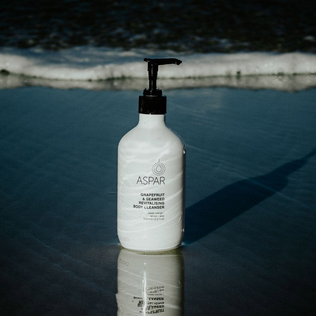 White bottle with black pump labeled 'ASPAR' on a reflective surface.