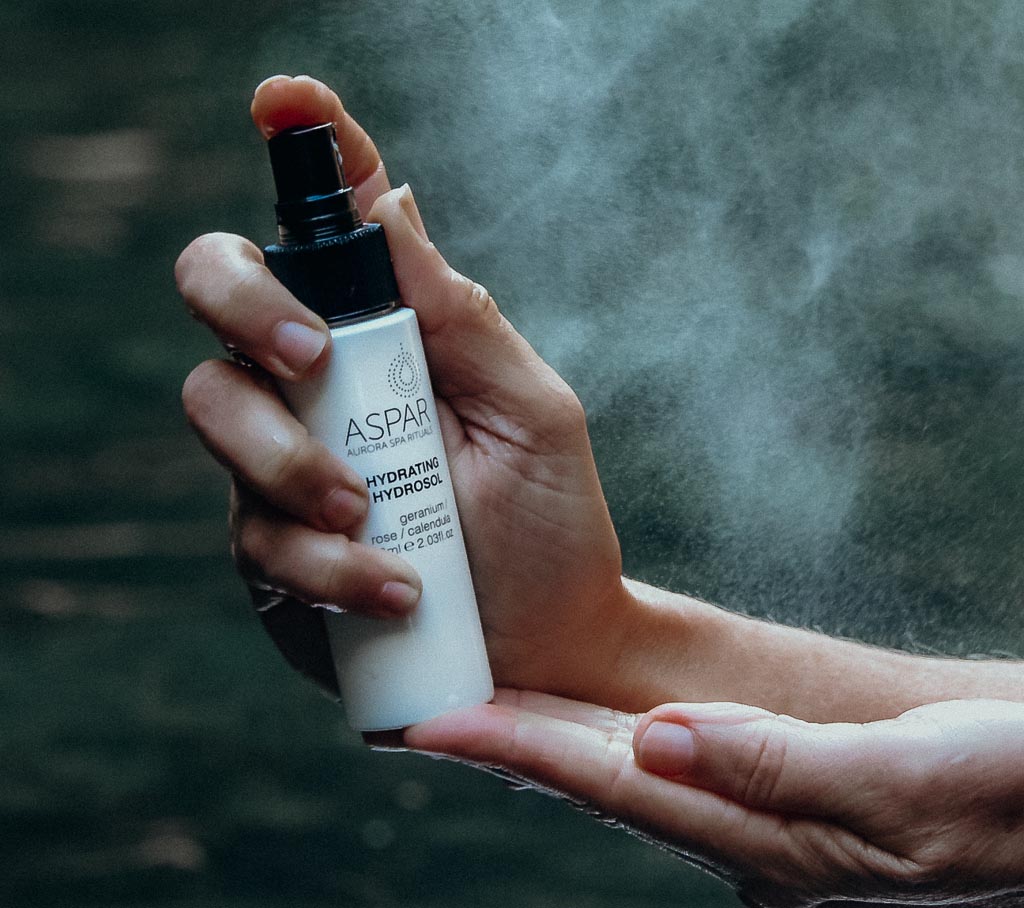 Hand holding a ASPAR skincare product with a blurred natural background
