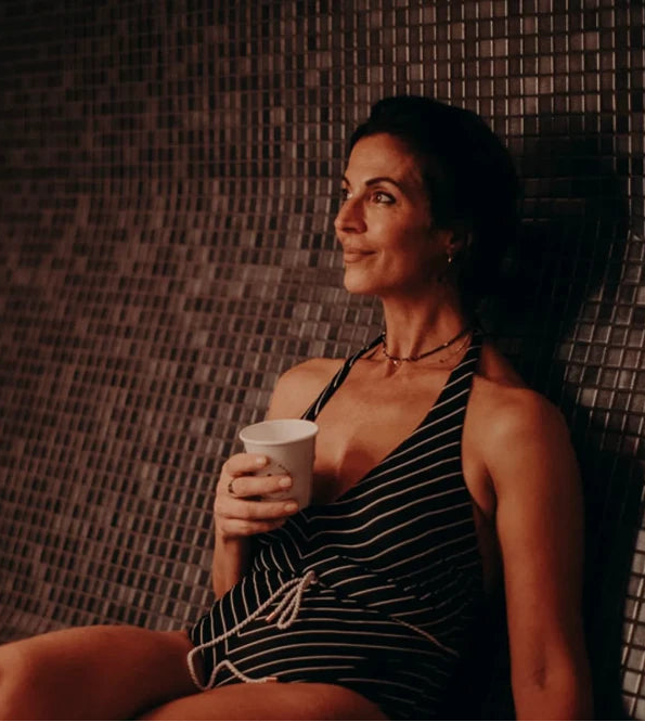 Woman sitting in a tiled room holding a cup
