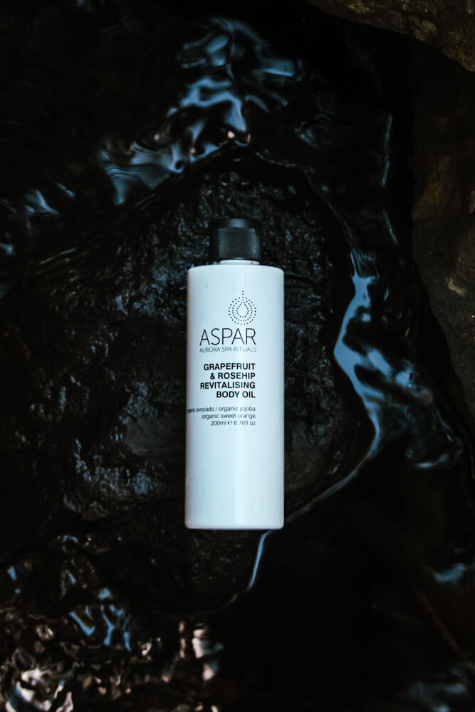 Aspar body oil bottle on a dark textured surface
