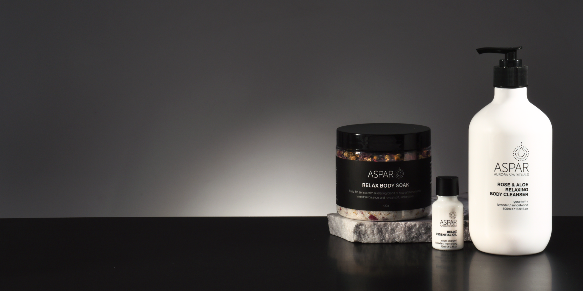 Aspar skincare products on a black surface with a dark background