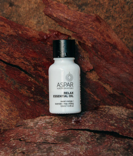 Bottle of ASPAR Relax Essential Oil on a textured brown surface