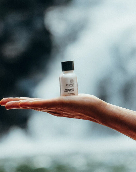 Hand holding a small bottle with a blurred natural background