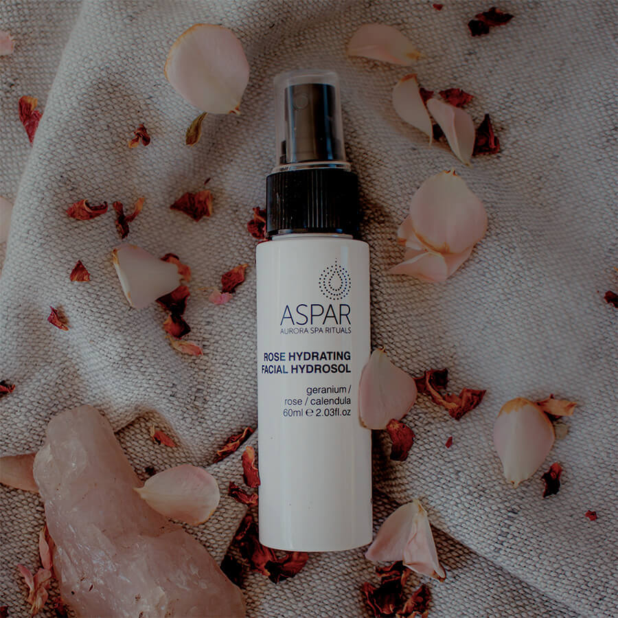 Aspar facial hydrosol bottle on a textured surface with flowers and crystals