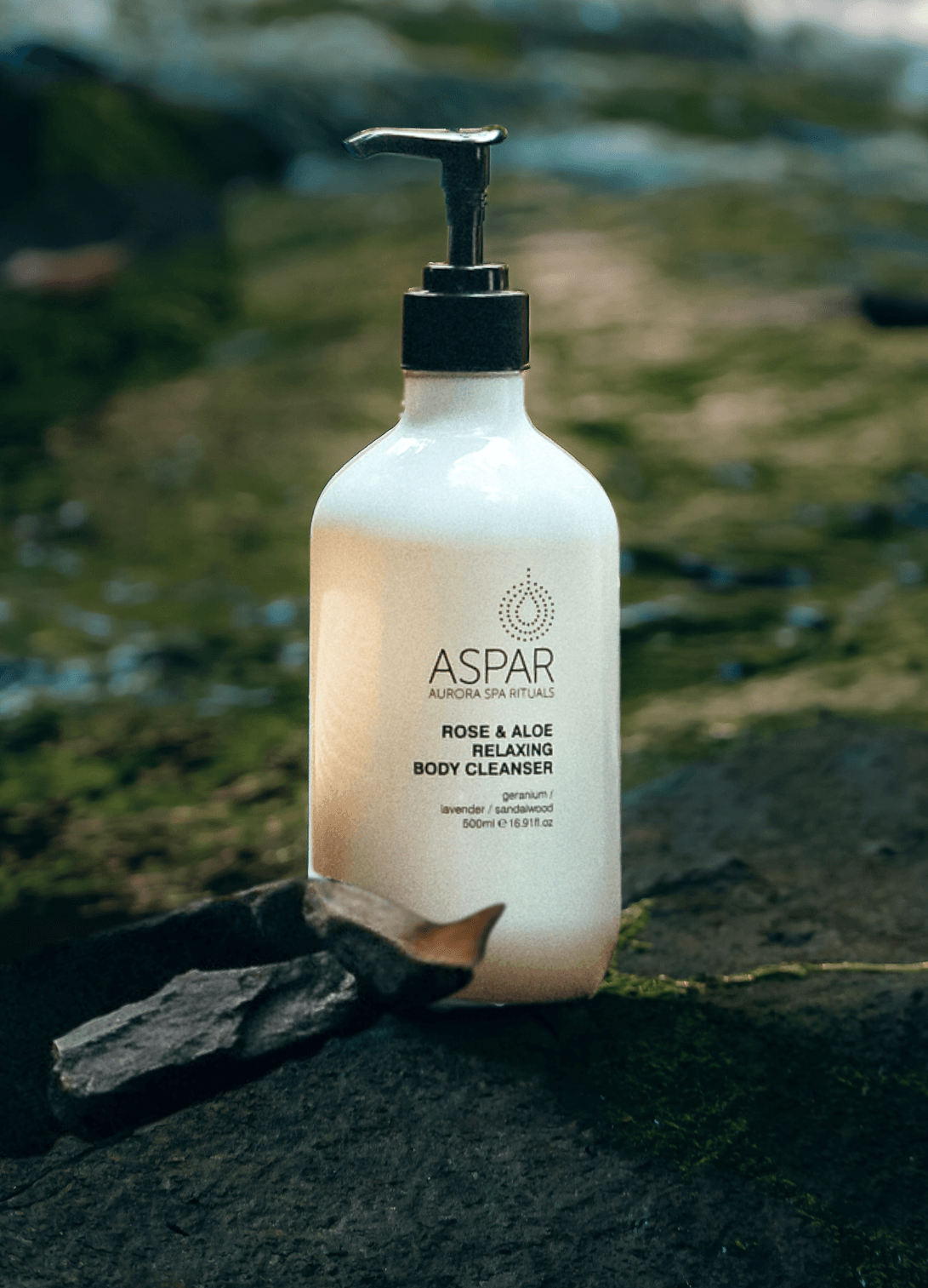 White bottle of Aspar body cleanser with pump on a natural stone surface