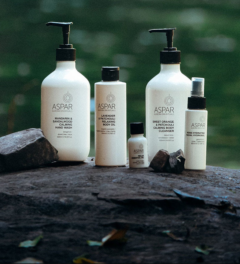 Collection of Aspar skincare products on a rock with a natural background