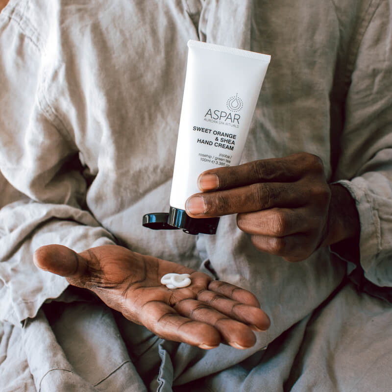 Person holding a tube of Aspar hand cream with a small amount on their palm.