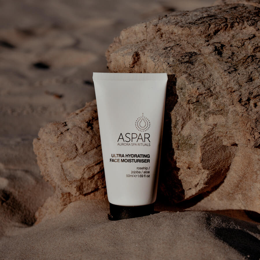 Tube of Aspar ultra hydrating face moisturizer on a rock with sand in the background